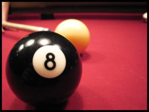 eight ball in foreground, cue ball behind with cue lining up on left