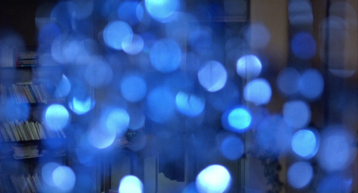 extreme close-up of blue glass bead mobile with book shelves visible behind